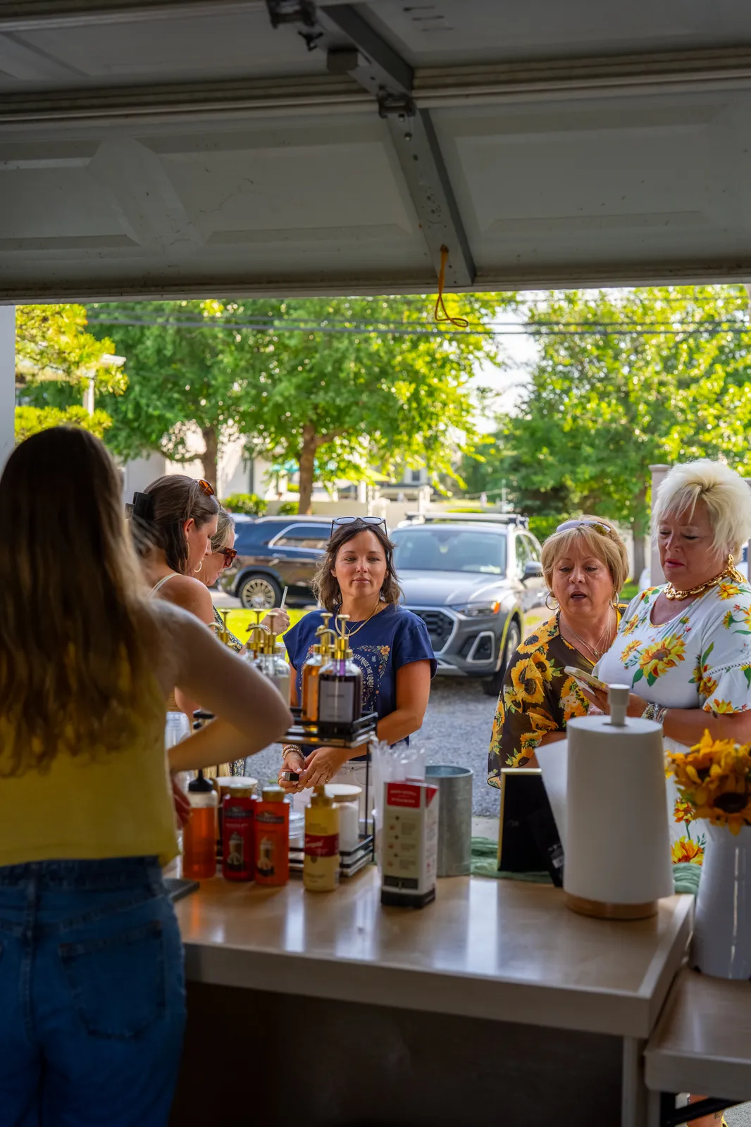 Three guests stand at the cart in daylight, ordering drinks beside branded syrup bottles.